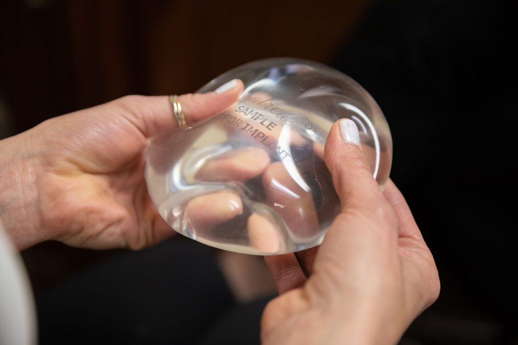 Two hands hold breast implants