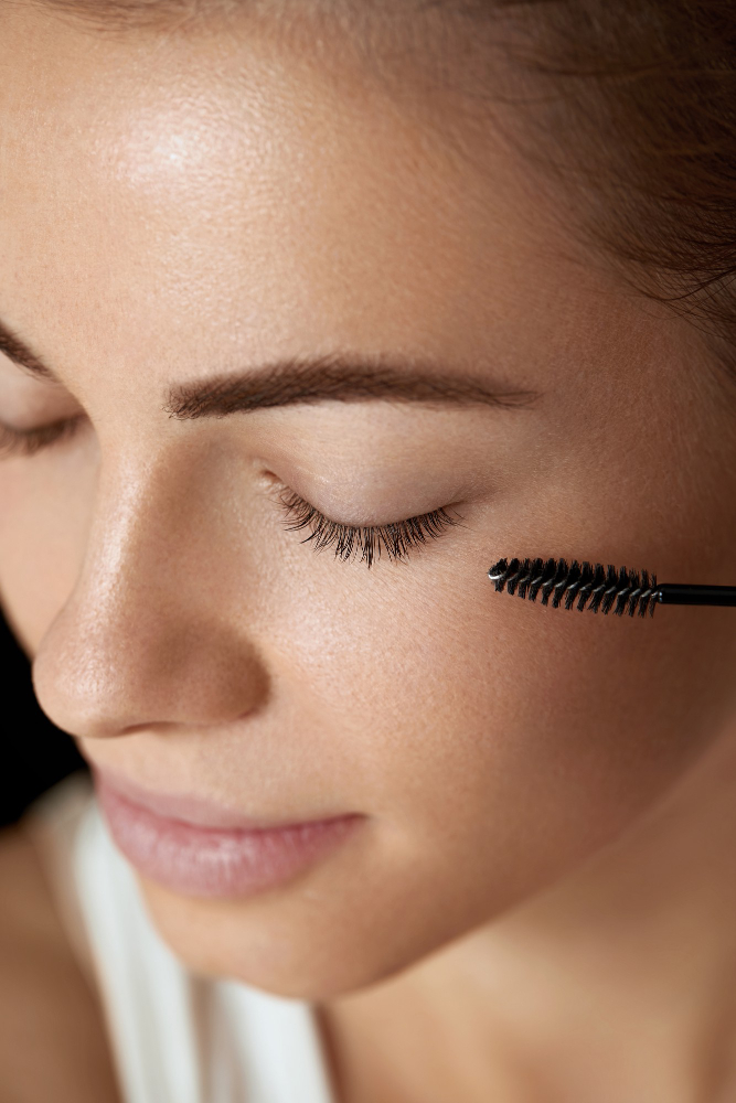 Woman softly closing eyes as a provider places a mascara brush near her.