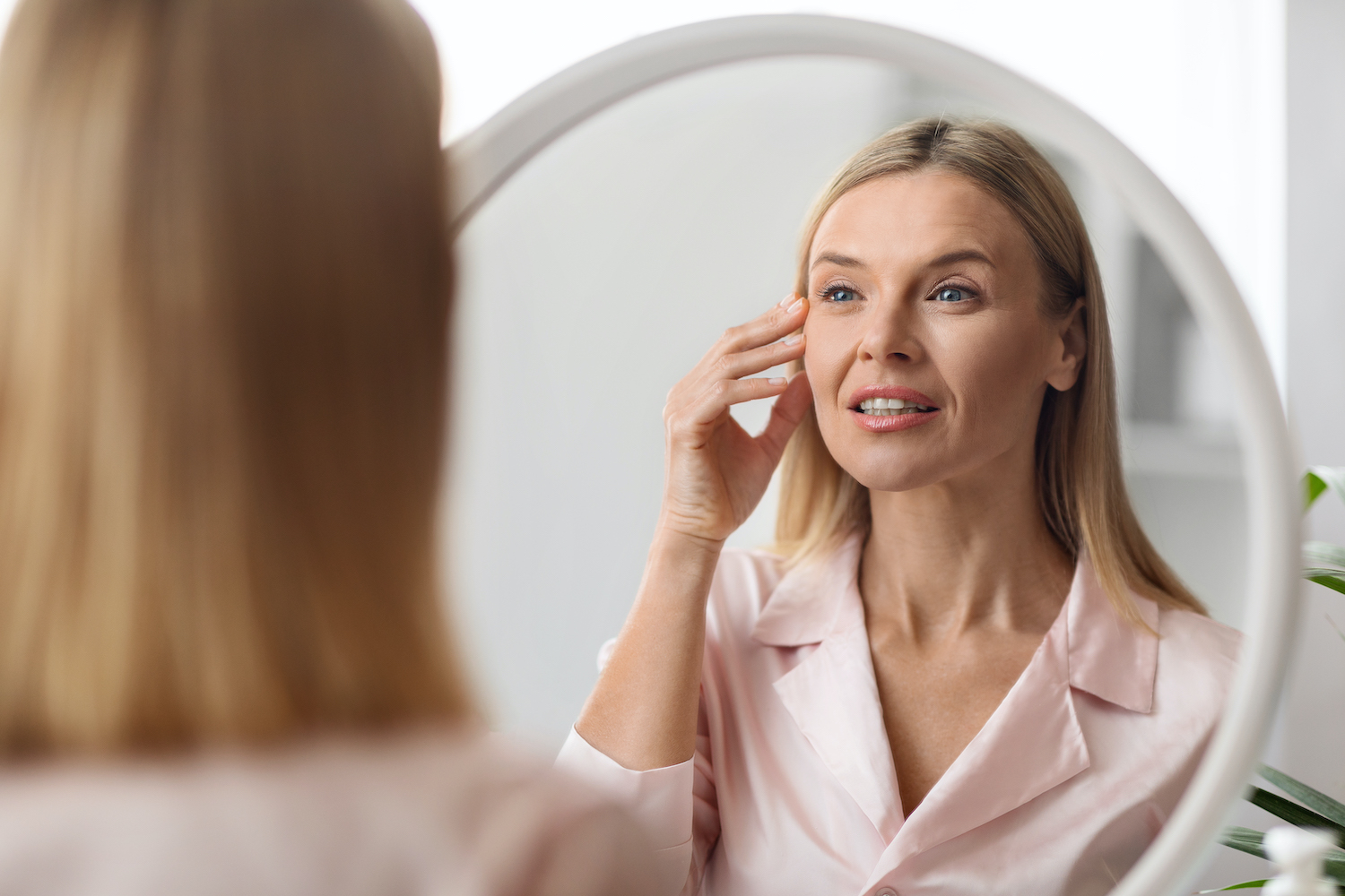 A patient examines her face, considering facial plastic surgery in Indiana.